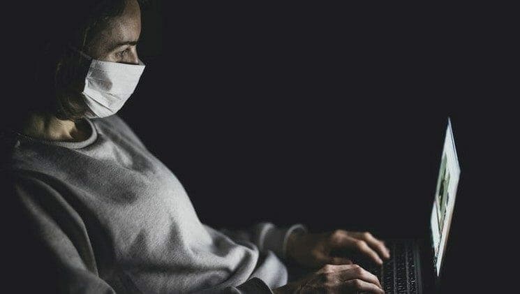 Person on laptop wearing a mask